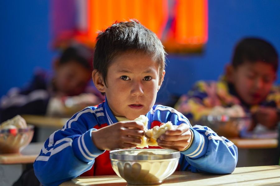 Un écolier en première année prend un déjeuner gratuit sur le nouveau campus d'une école à Daliyaboyi, bourg du district de Yutian, dans la région autonome ouïgoure du Xinjiang (nord-ouest), le 19 novembre 2019. (Photo : Shen Bohan)