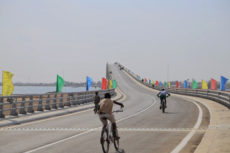 Des gens font du vélo sur le pont de Foundiougne, dans la région de Fatick, au Sénégal, le 16 janvier 2022. (Xinhua/Wang Zizheng)