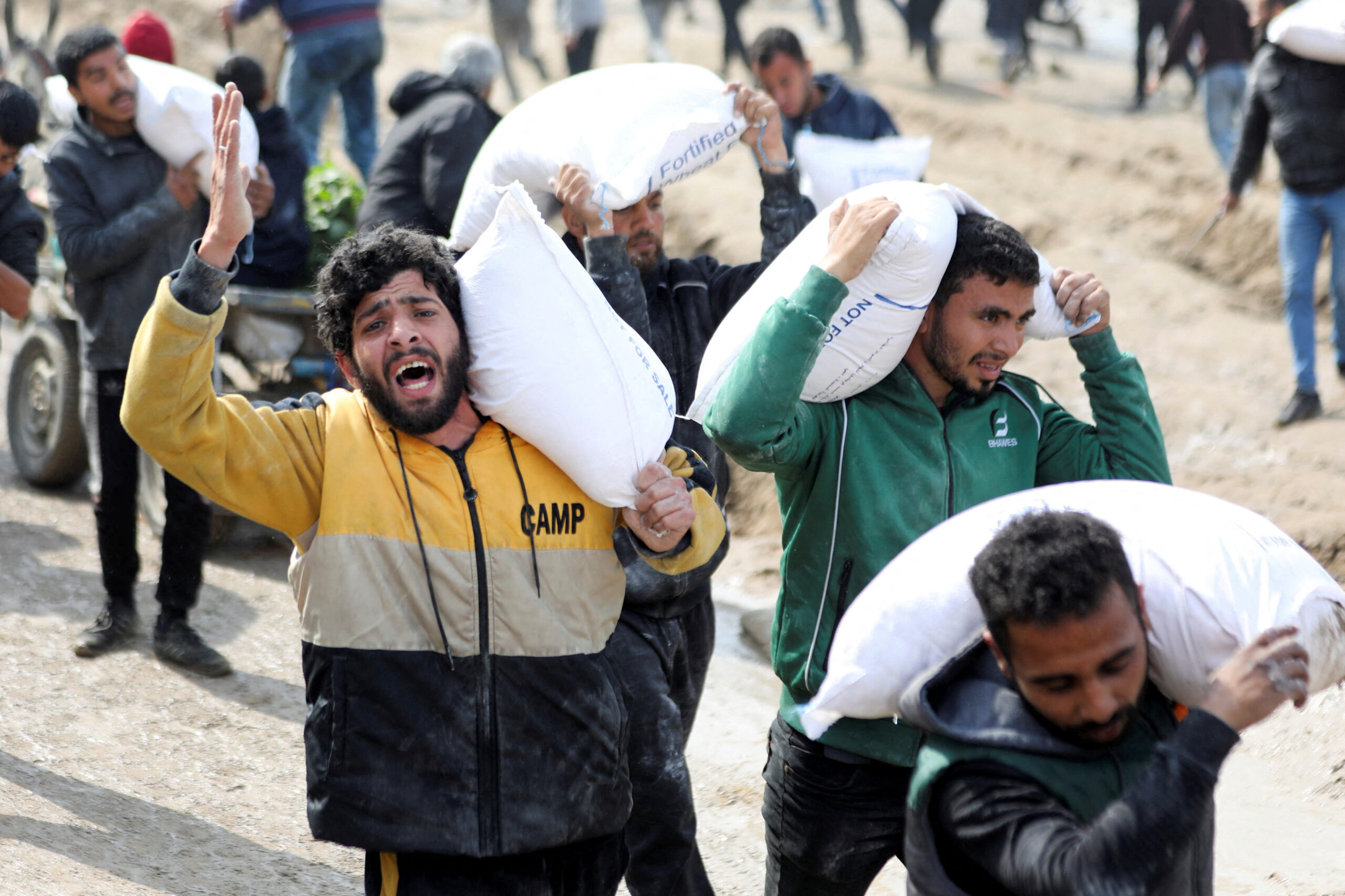 Des Palestiniens transportent des sacs de farine récupérés dans un camion humanitaire à Gaza. /Photo prise le 19 février 2024/REUTERS/Kosay Al Nemer