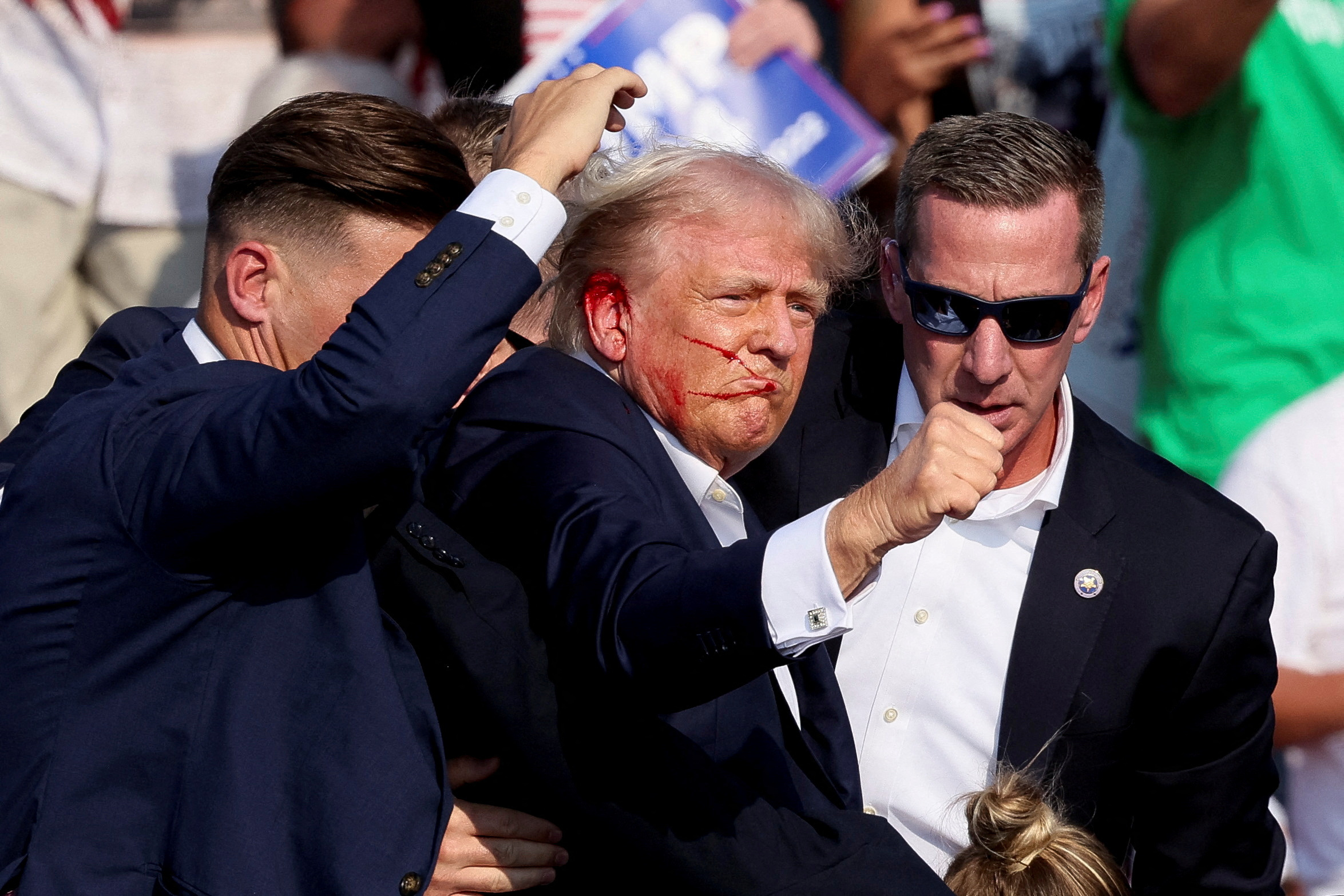 Le candidat républicain à la présidence et ancien président des États-Unis Donald Trump fait un geste alors qu'il est aidé par le personnel de sécurité après que des coups de feu ont retenti lors d'un rassemblement de campagne au Butler Farm Show à Butler, Pennsylvanie, États-Unis/Photo prise 13 juillet 2024/REUTERS/Brendan McDermid