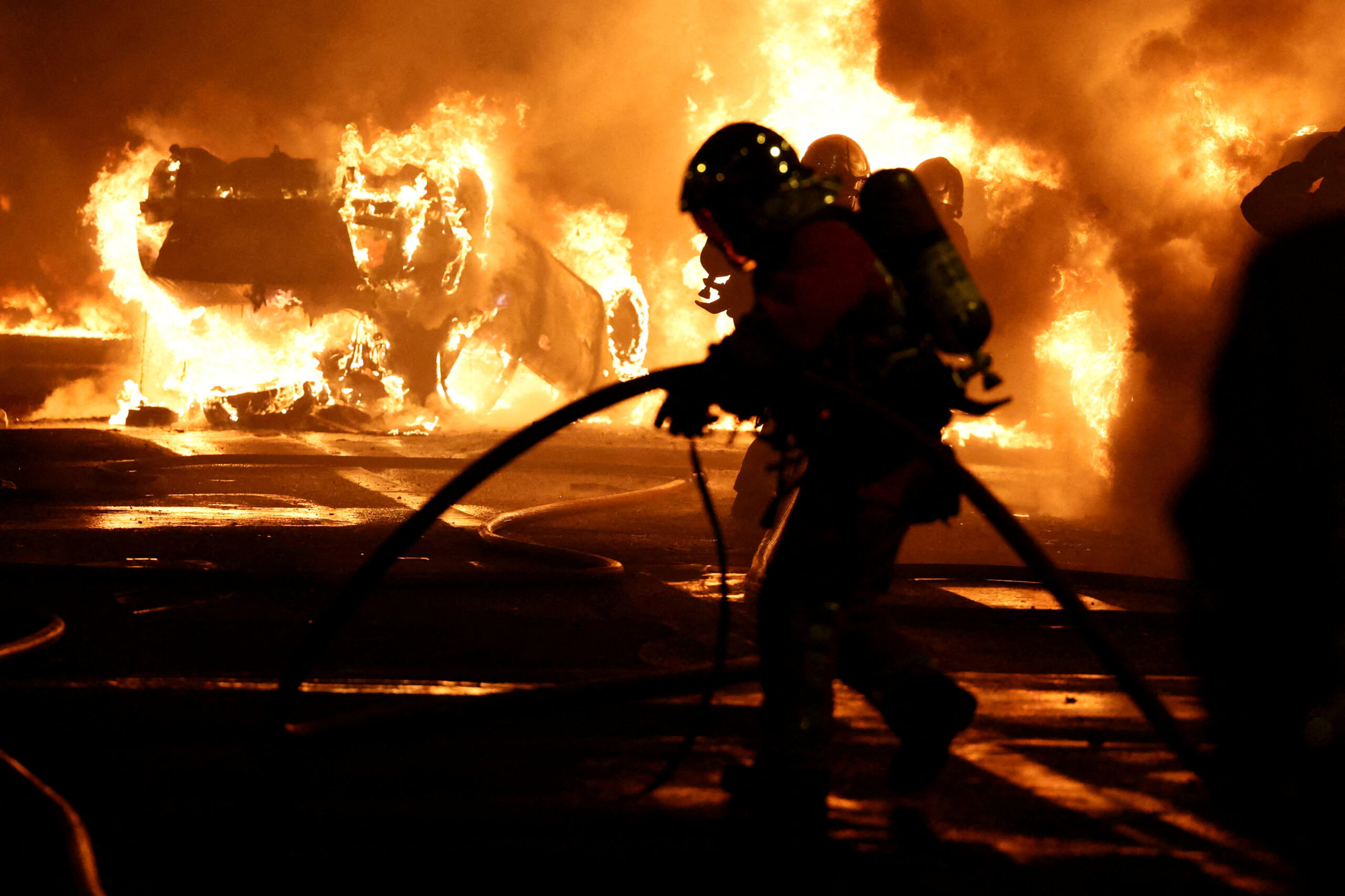 Des pompiers éteignent des véhicules en feu lors d'affrontements entre des manifestants et des policiers, après la mort de Nahel, un adolescent de 17 ans tué par un policier ors d'un contrôle routier, à Nanterre, dans la banlieue parisienne, en France./Photo prise le 28 juin 2023/REUTERS/Stephanie Lecocq