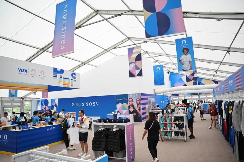 Des visiteurs choisissent des souvenirs dans une boutique officielle agréée dans le Village olympique avant les Jeux olympiques de Paris 2024, en France, le 23 juillet 2024. (Xinhua/Hu Huhu)