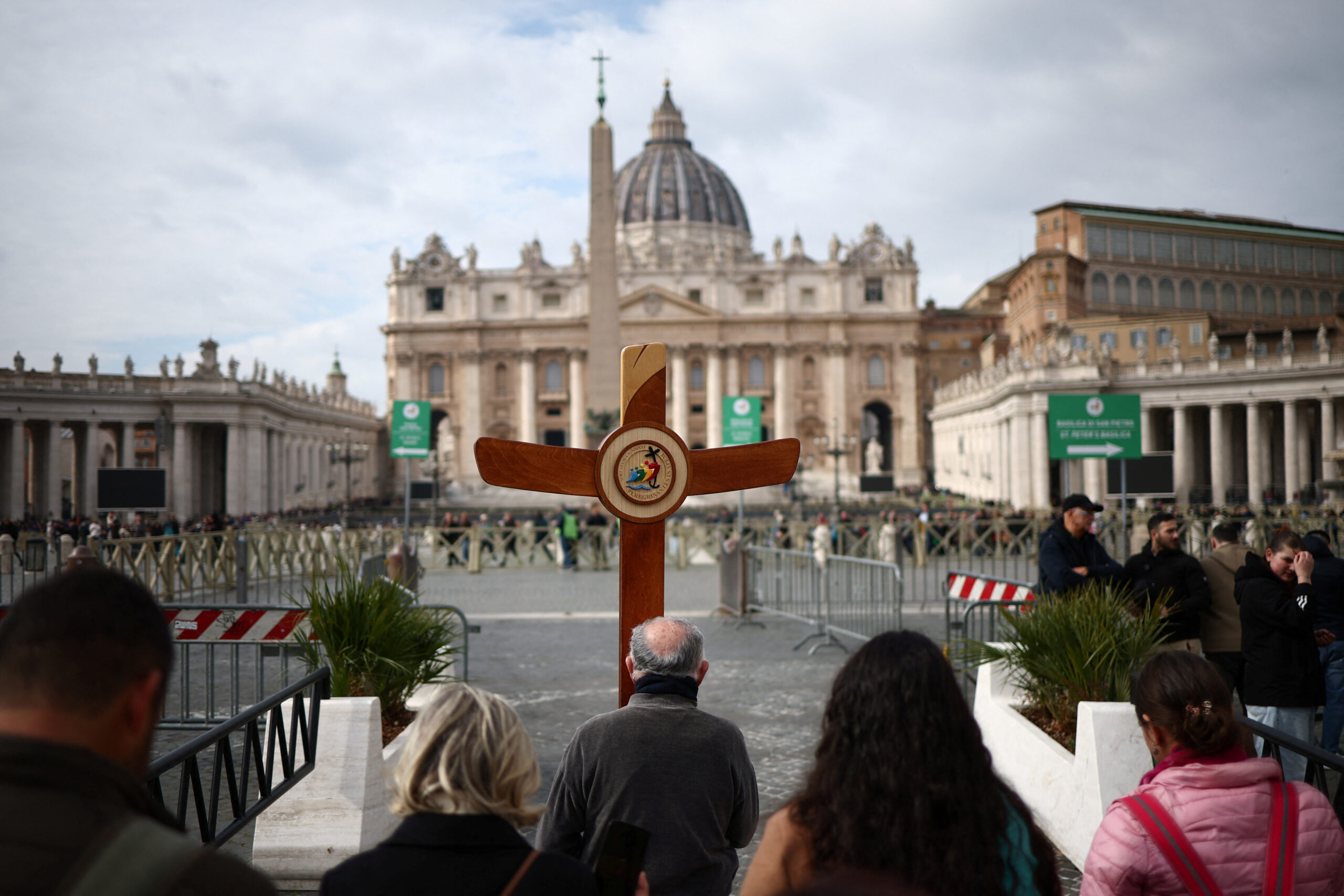 Des pèlerins portent une croix sur la place Saint-Pierre, au Vatican, alors que le pape François est admis pour poursuivre son traitement. /Photo prise le 18 février 2025/REUTERS/Guglielmo Mangiapane